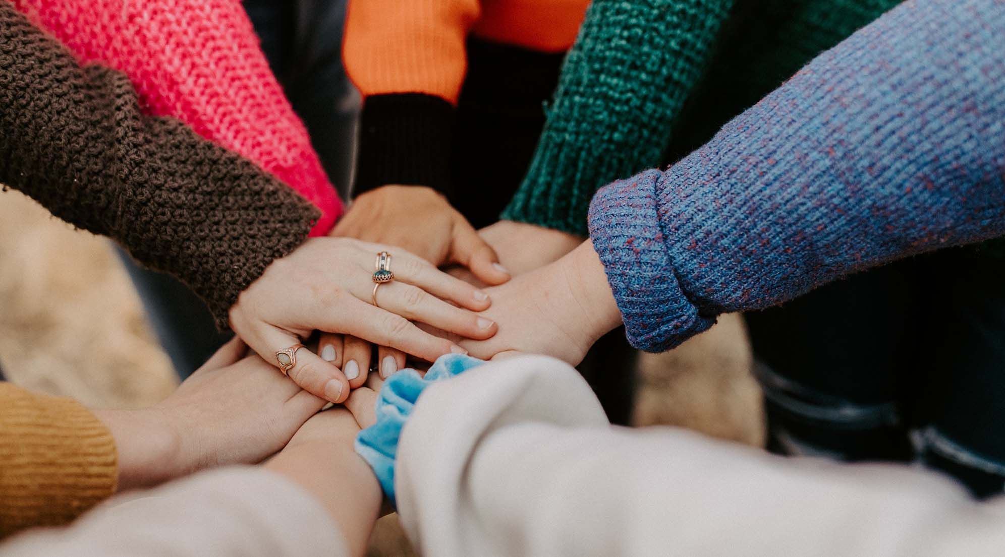 Several people placing their hands in the middle of a circle.